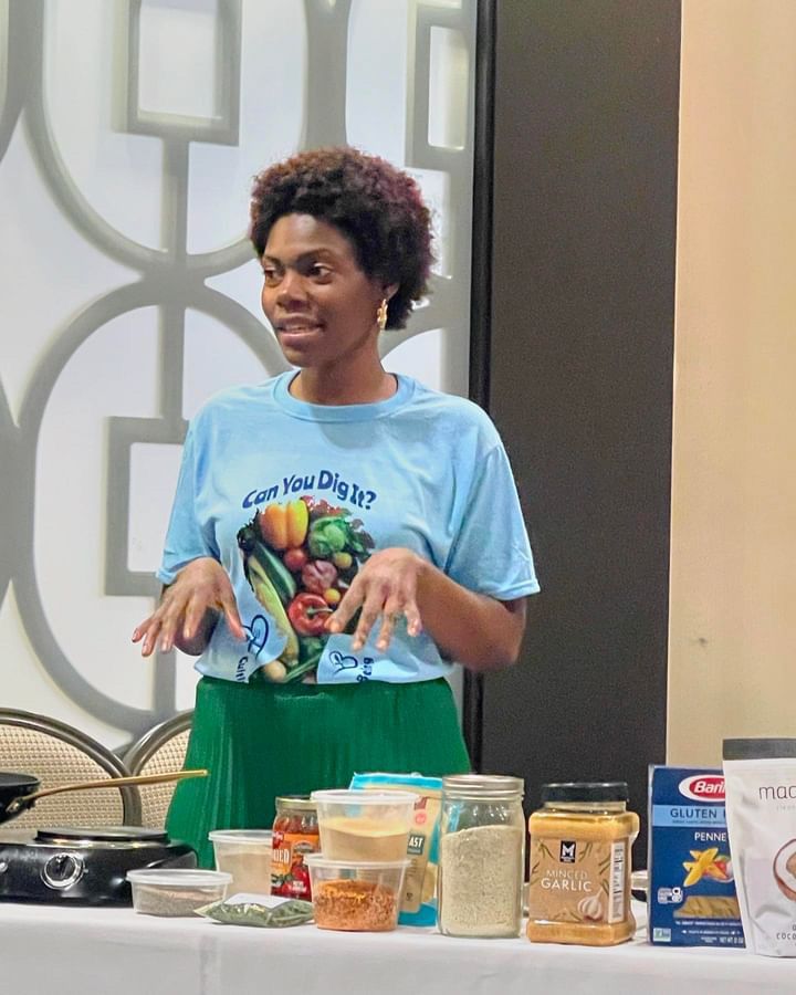 A woman is preparing food at a table in a park.