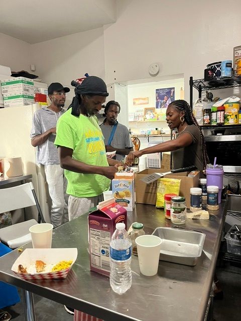A group of people are standing around a table in a park.