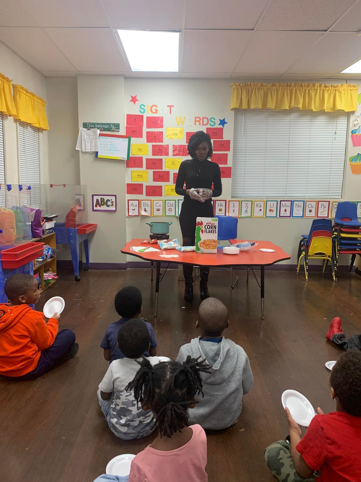 A woman is giving a presentation to a group of children in a classroom.
