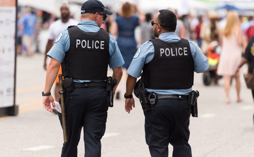 Two police officers are walking down a street.