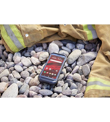 A cell phone is sitting on top of a pile of rocks next to a fireman 's jacket.
