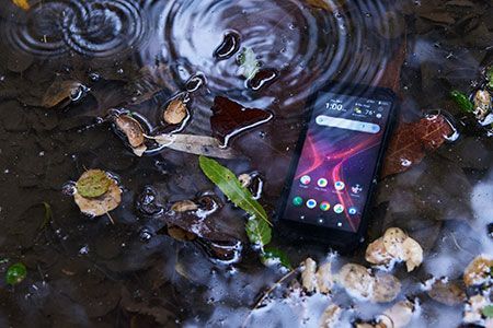 A cell phone is sitting in a puddle of water.