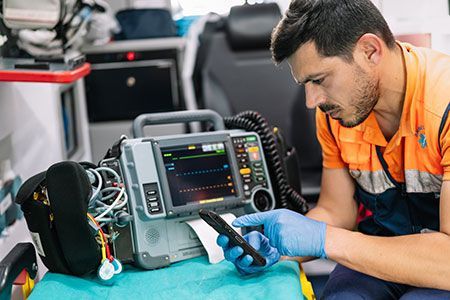 A man is working on a defibrillator in an ambulance.