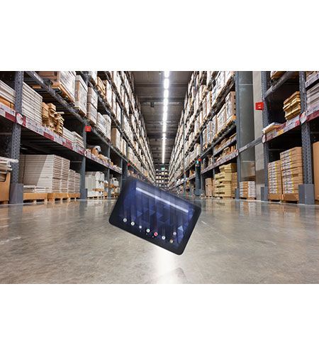 A tablet is laying on the floor of a warehouse.