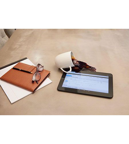 A tablet is sitting on a table next to a cup of coffee and a notebook.