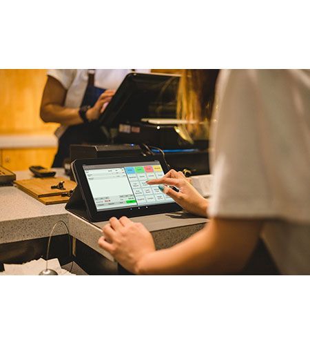 A person is using a tablet computer at a counter in a restaurant.