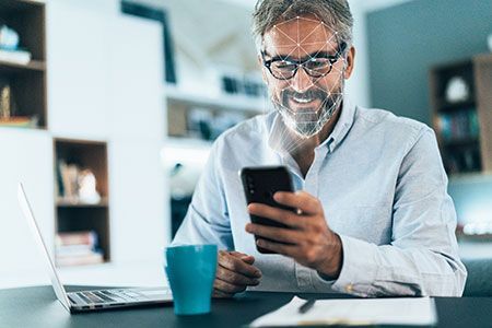 A man is sitting at a desk using a cell phone.