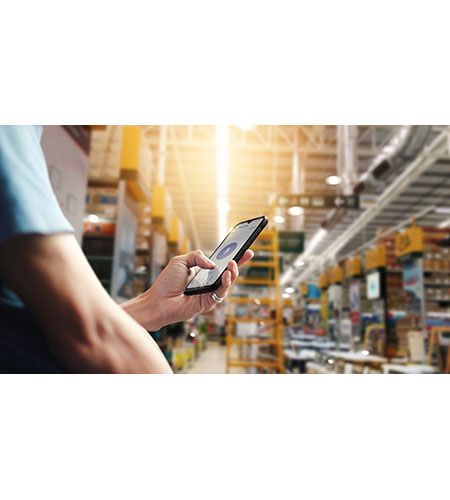 A man is holding a cell phone in a warehouse.