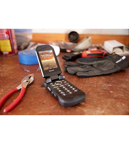 A flip phone is sitting on a table next to gloves and pliers.
