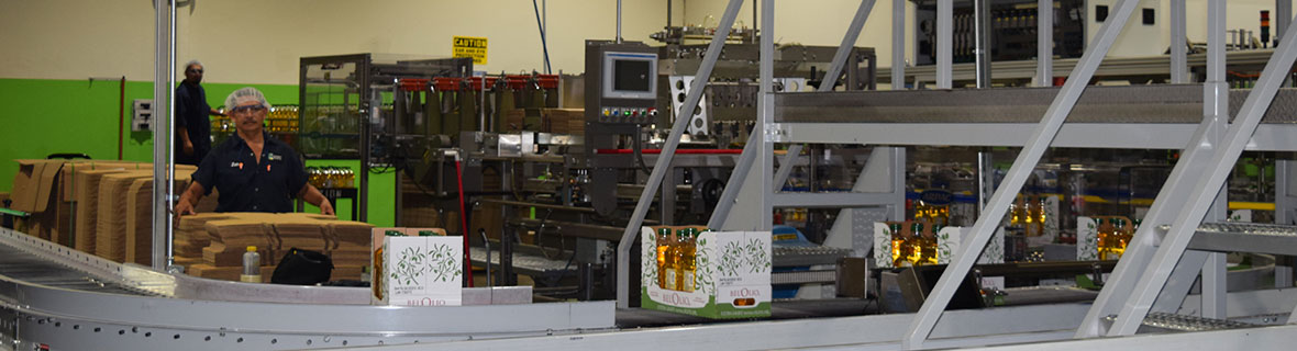 A man is sitting at a table in a factory looking at a machine.