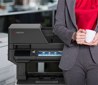 A woman is holding a cup of coffee in front of a kyocera printer