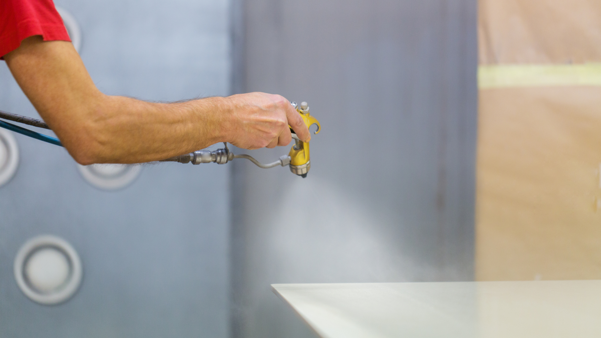A man is spraying paint on a piece of wood.