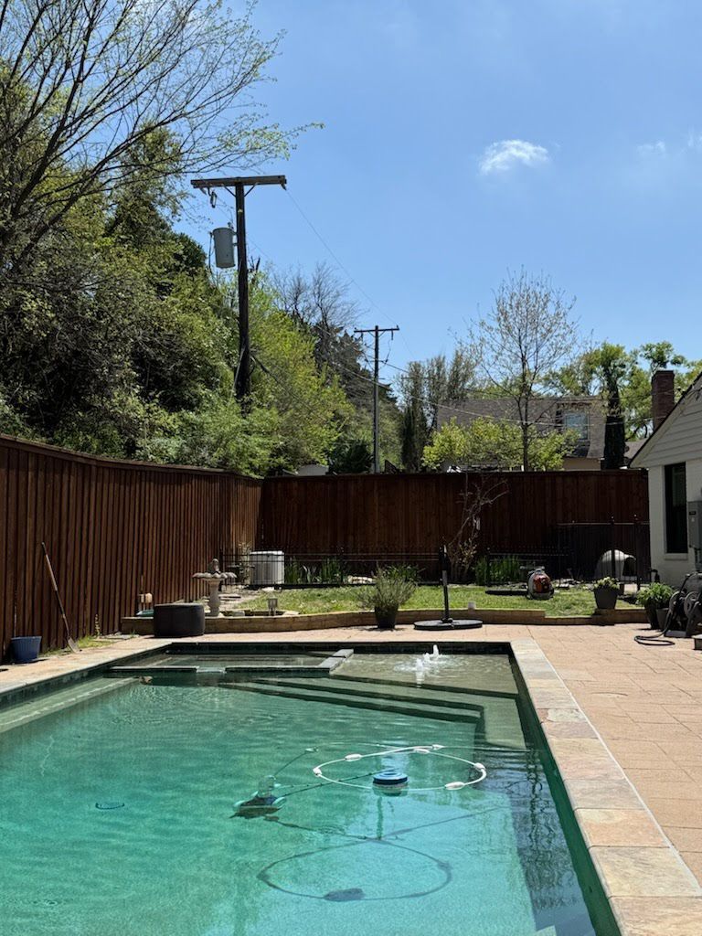 A large swimming pool in a backyard with a wooden fence surrounding it.