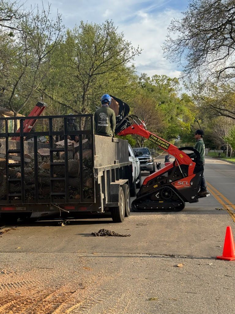 A man is standing on top of a trailer next to a tractor.