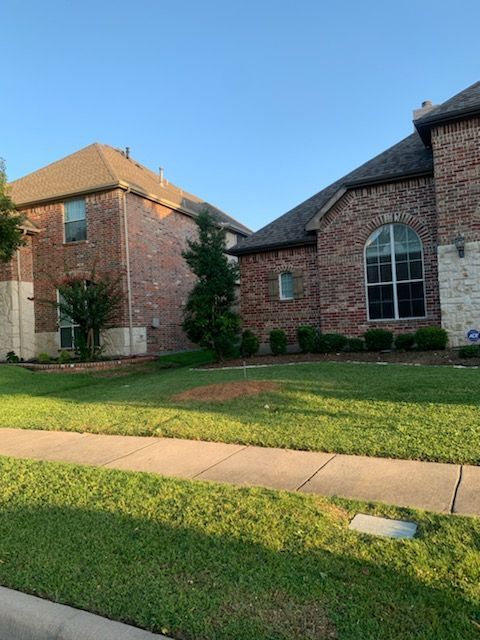 A brick house with a lush green lawn in front of it