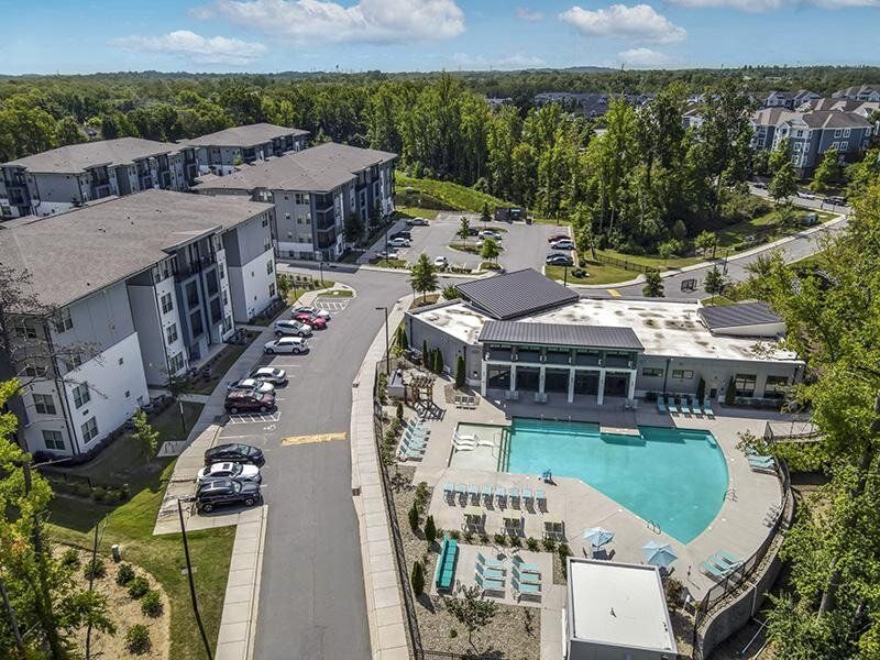 Aerial view of a multi-building apartment community with a central swimming pool and lounge areas.