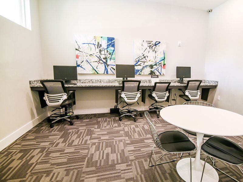 Community computer lab with four workstations along a counter and a round-table seating area.