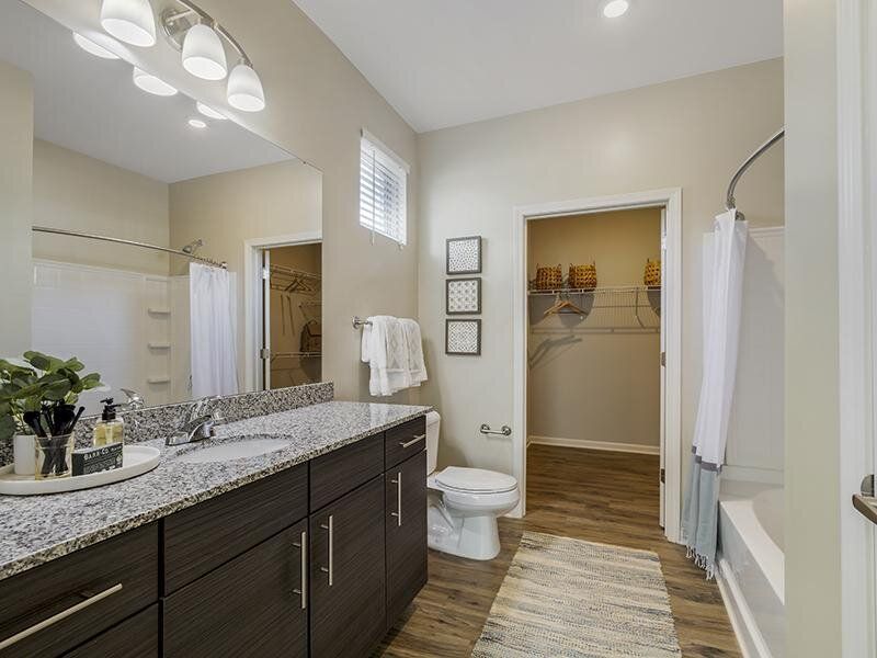 Modern bathroom with double vanity, granite countertop, and walk-in closet.