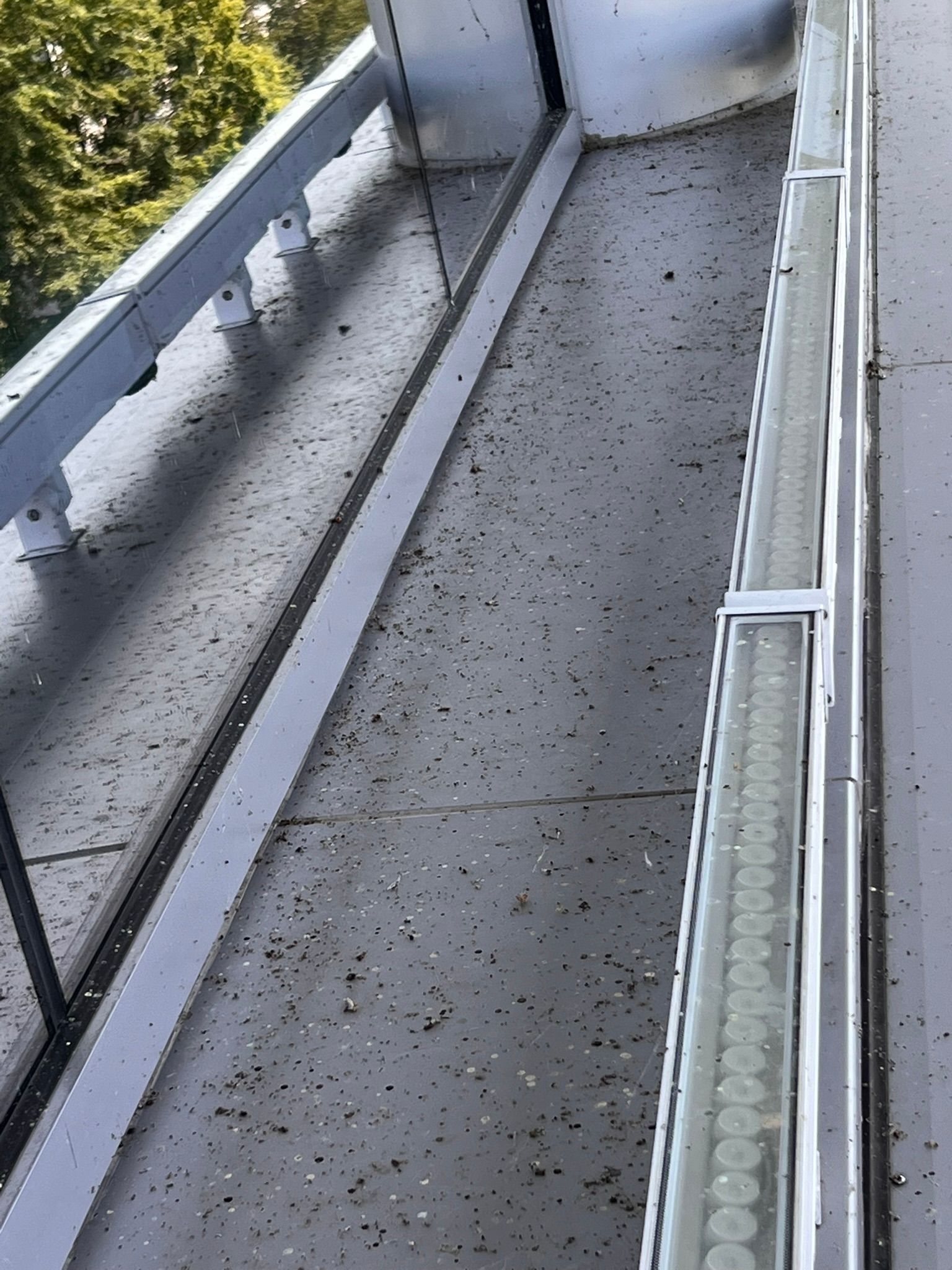 A balcony covered in debris; silver railing and a light fixture are visible.