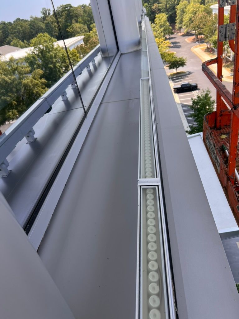 View from a high angle of a building's exterior with linear lights. An orange lift is visible.