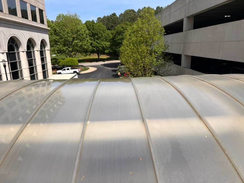 Wooden horizontal blinds, partially closed, showing a glimpse of the outside.