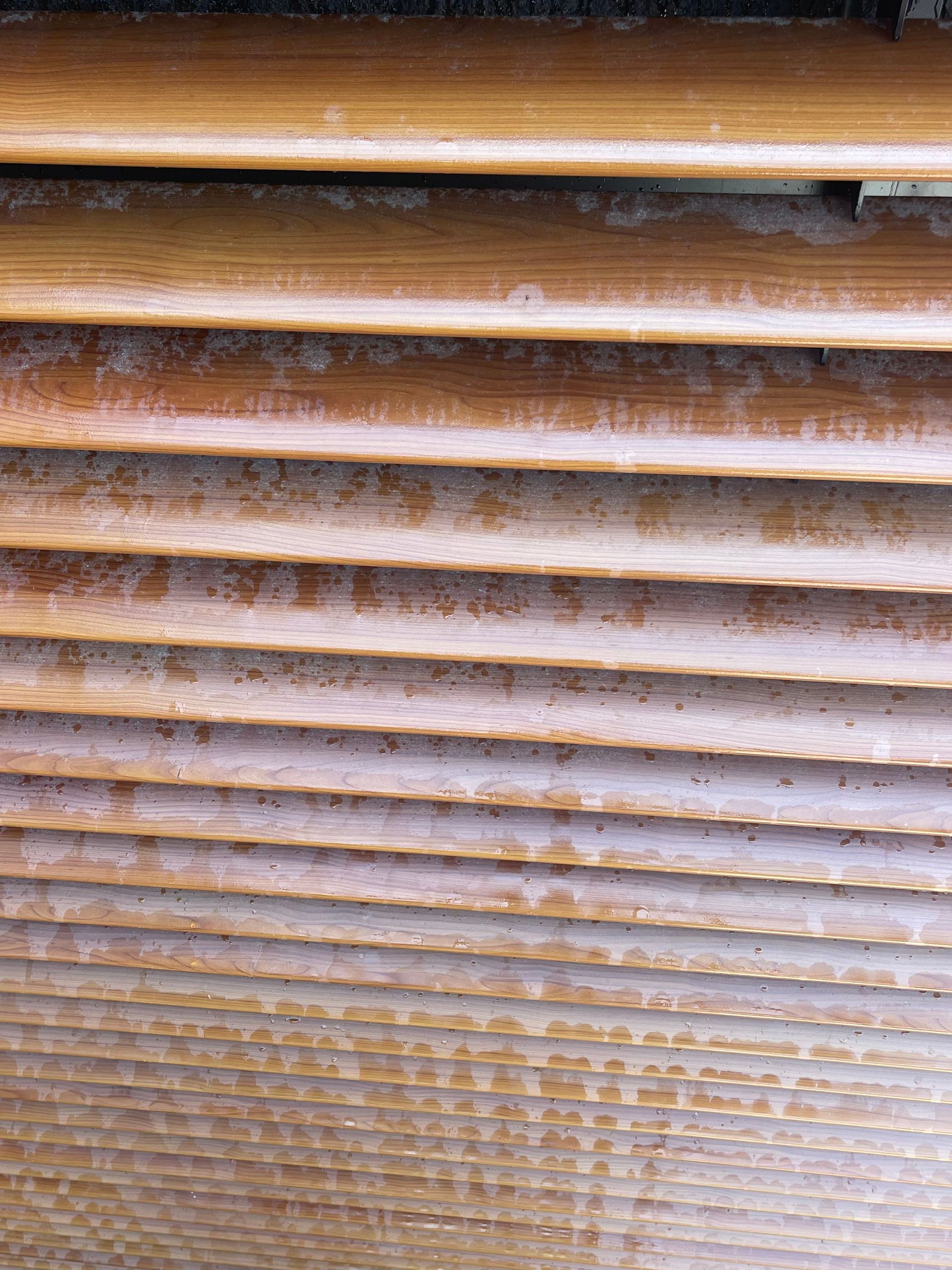 Wooden window shutters, horizontal slats, weathered appearance.