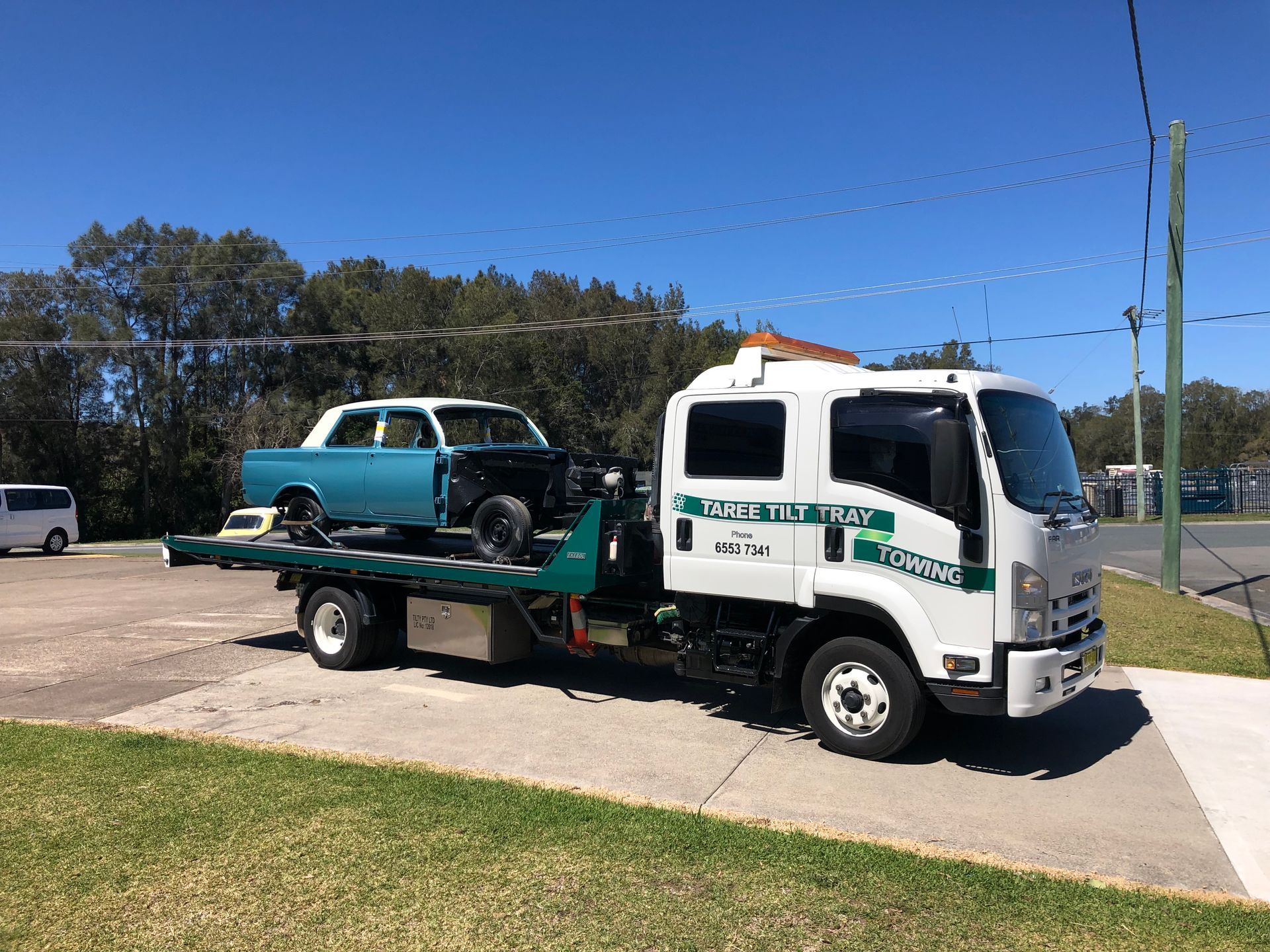 A Tow Truck Is Towing A Forklift In A Parking Lot — Taree Tilt Tray Towing In Pampoolah, NSW