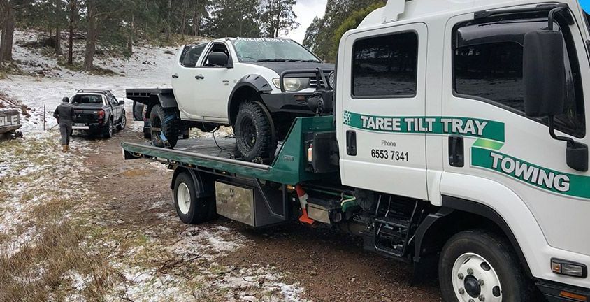 A Tow Truck is Towing a White Truck — Taree Tilt Tray Towing In Nabiac, NSW