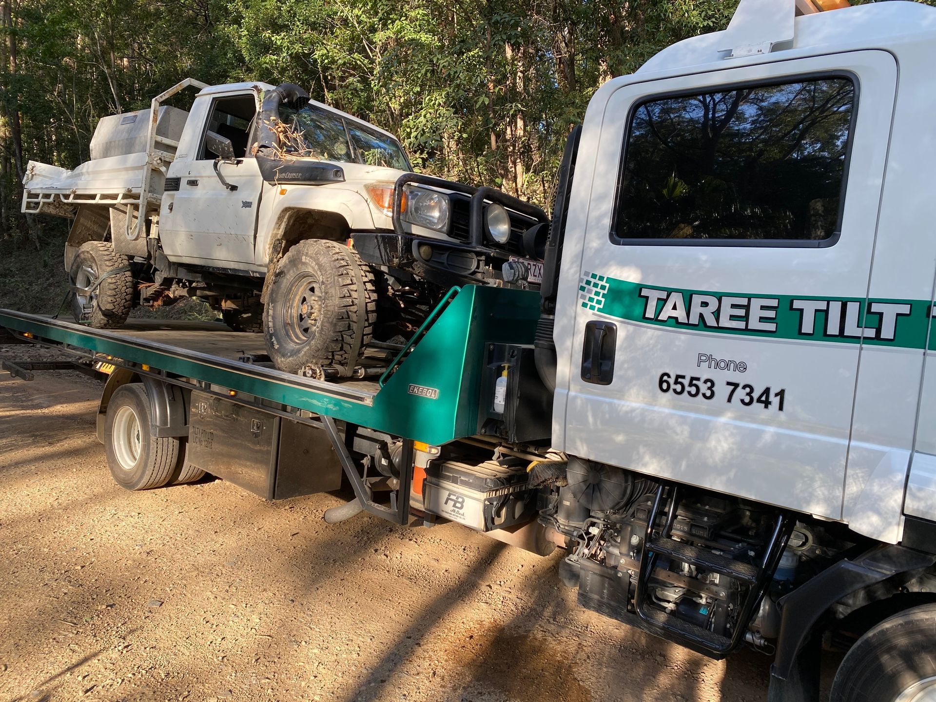 A Tow Truck is Carrying a Car on a Trailer — Taree Tilt Tray Towing In Pampoolah, NSW