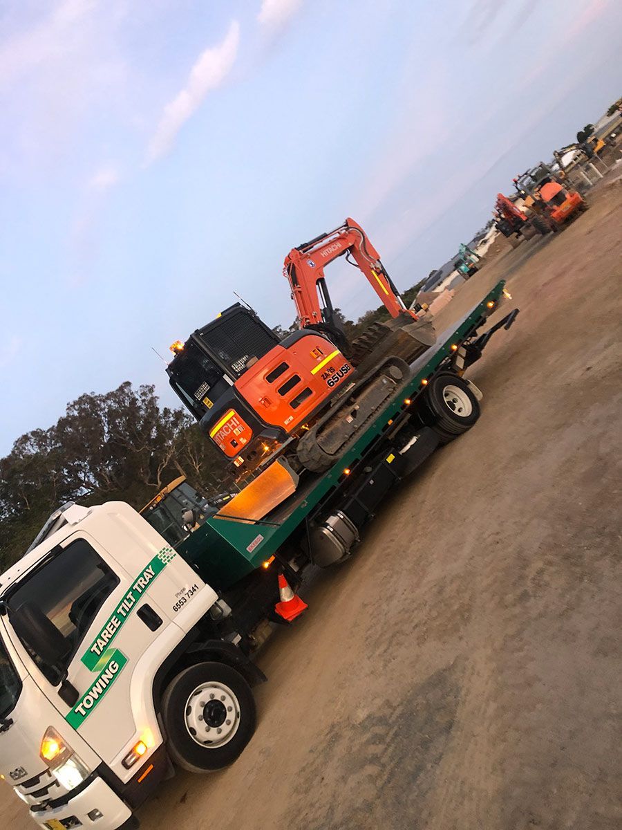 A Tow Truck With An Excavator On The Back Of It — Taree Tilt Tray Towing In Tuncurry, NSW