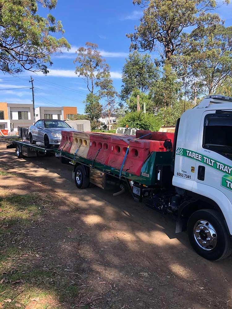 A Tow Truck Is Carrying A Car On A Trailer — Taree Tilt Tray Towing In Pampoolah, NSW