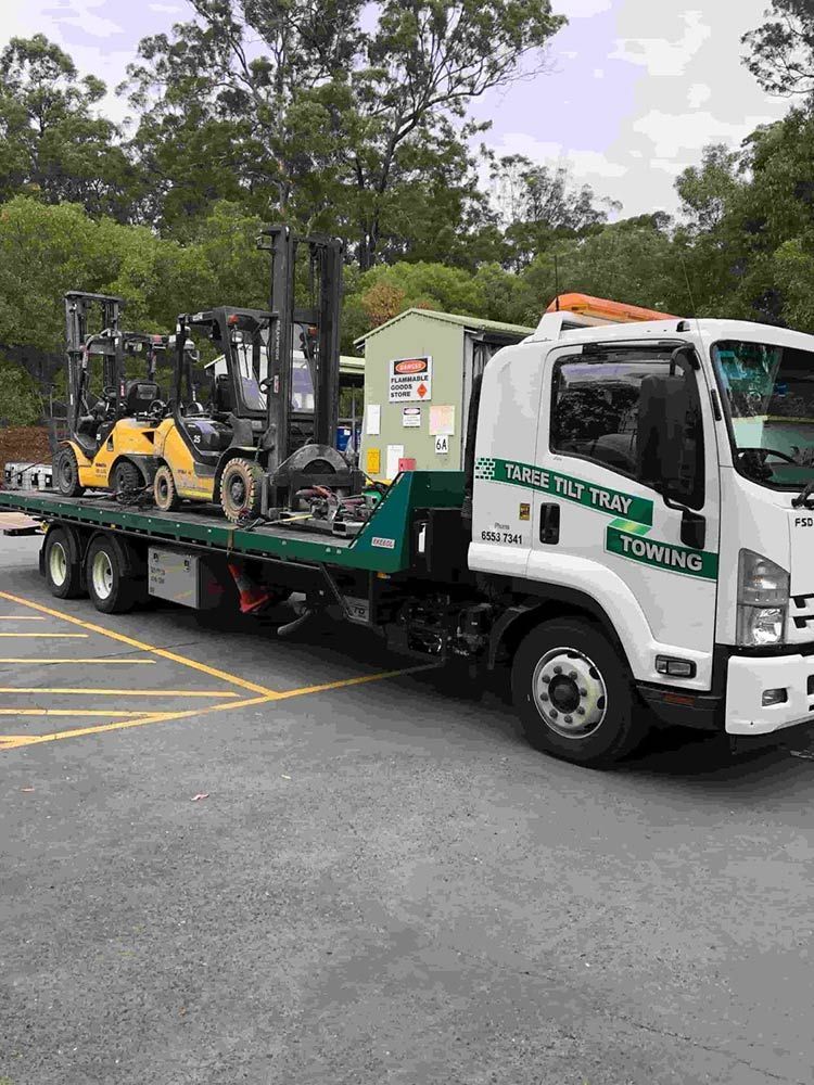 A Tow Truck Is Carrying Two Forklifts On The Back Of It — Taree Tilt Tray Towing In Pampoolah, NSW