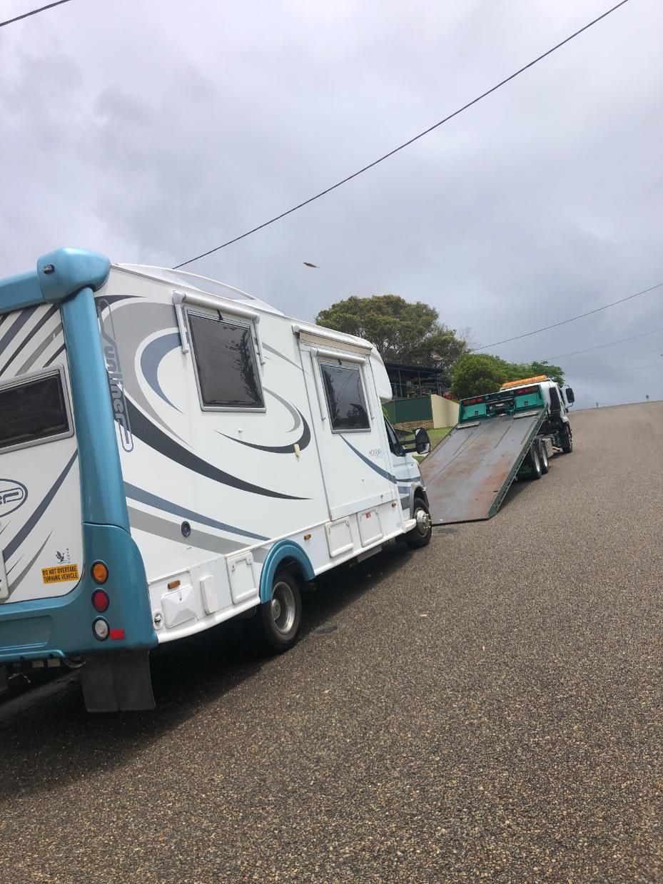 A RV Is Being Towed Down A Road By A Tow Truck — Taree Tilt Tray Towing In Pampoolah, NSW