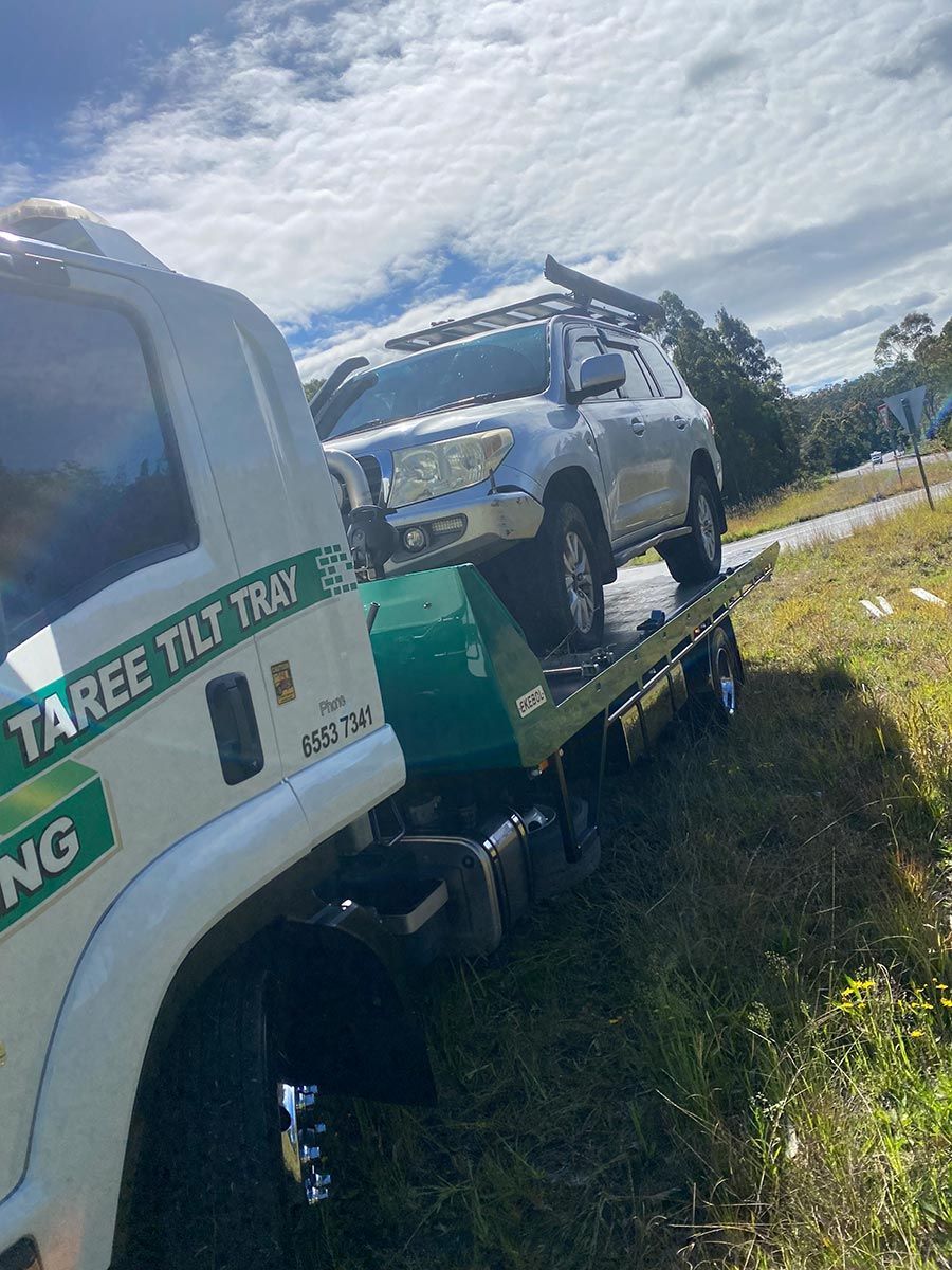 A Car is Being Towed by a Tow Truck — Taree Tilt Tray Towing In Pampoolah, NSW