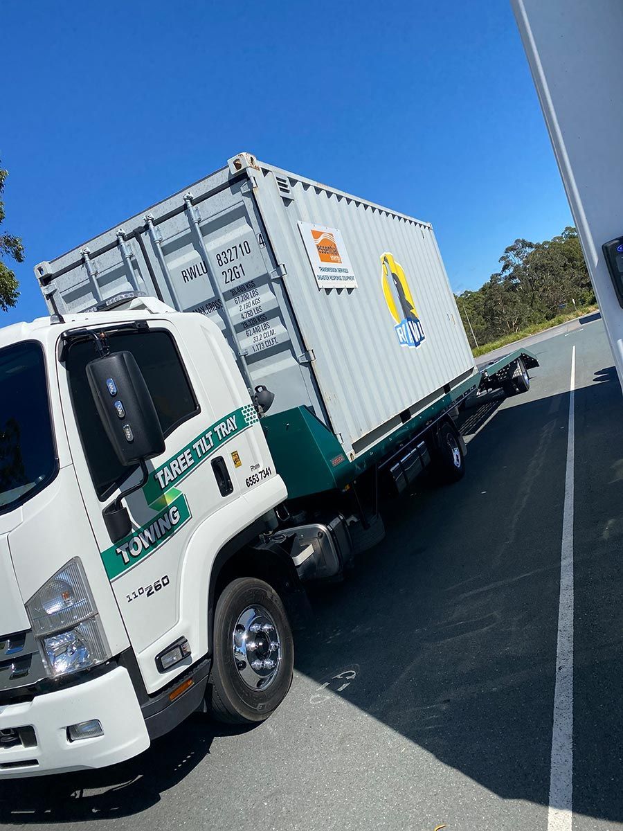 A White Truck With a Container on the Back is Parked on the Side of the Road — Taree Tilt Tray Towing In Pampoolah, NSW
