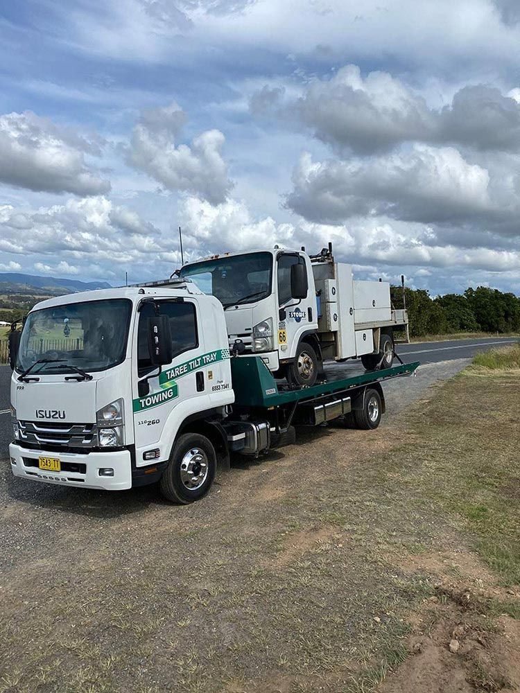 A Tow Truck Is Carrying Two Trucks On A Flatbed Trailer — Taree Tilt Tray Towing In Wootton, NSW