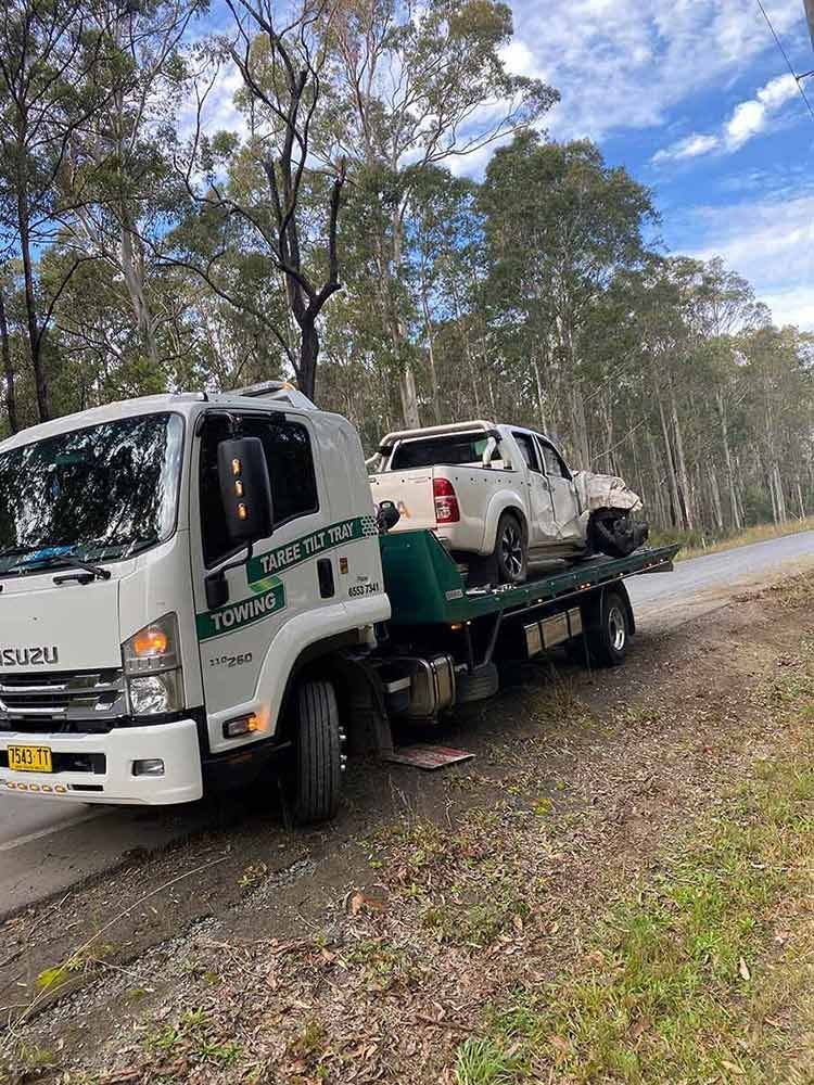 A Tow Truck Is Towing Two Cars Down A Road — Taree Tilt Tray Towing In Old Bar, NSW