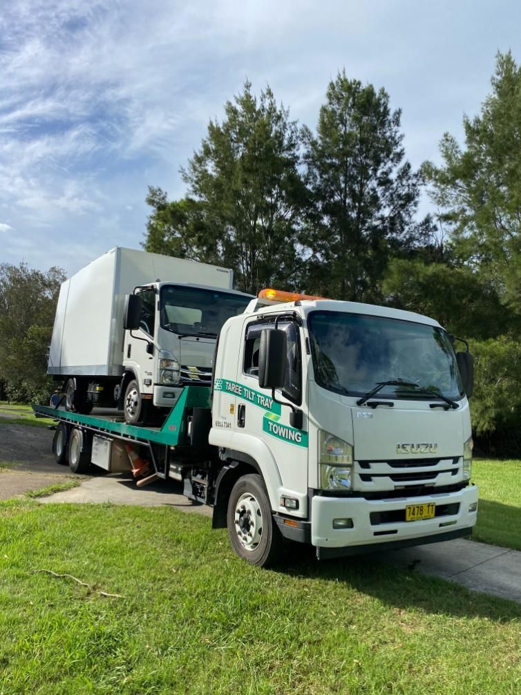 A White Tow Truck Is Carrying A White Truck On A Flatbed Trailer — Taree Tilt Tray Towing In Pampoolah, NSW