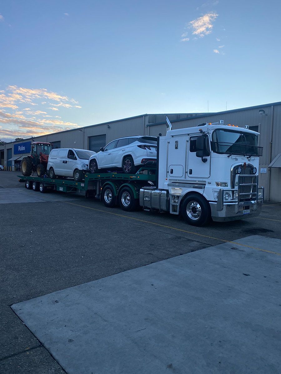 A White Semi Truck is Carrying a Trailer Full of Cars — Taree Tilt Tray Towing In Forster, NSW