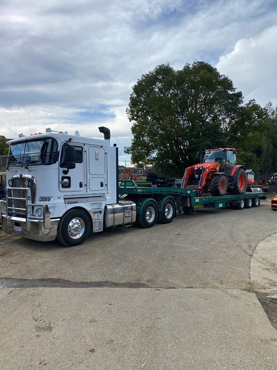 A Semi Truck is Carrying a Tractor on a Trailer — Taree Tilt Tray Towing In Pampoolah, NSW