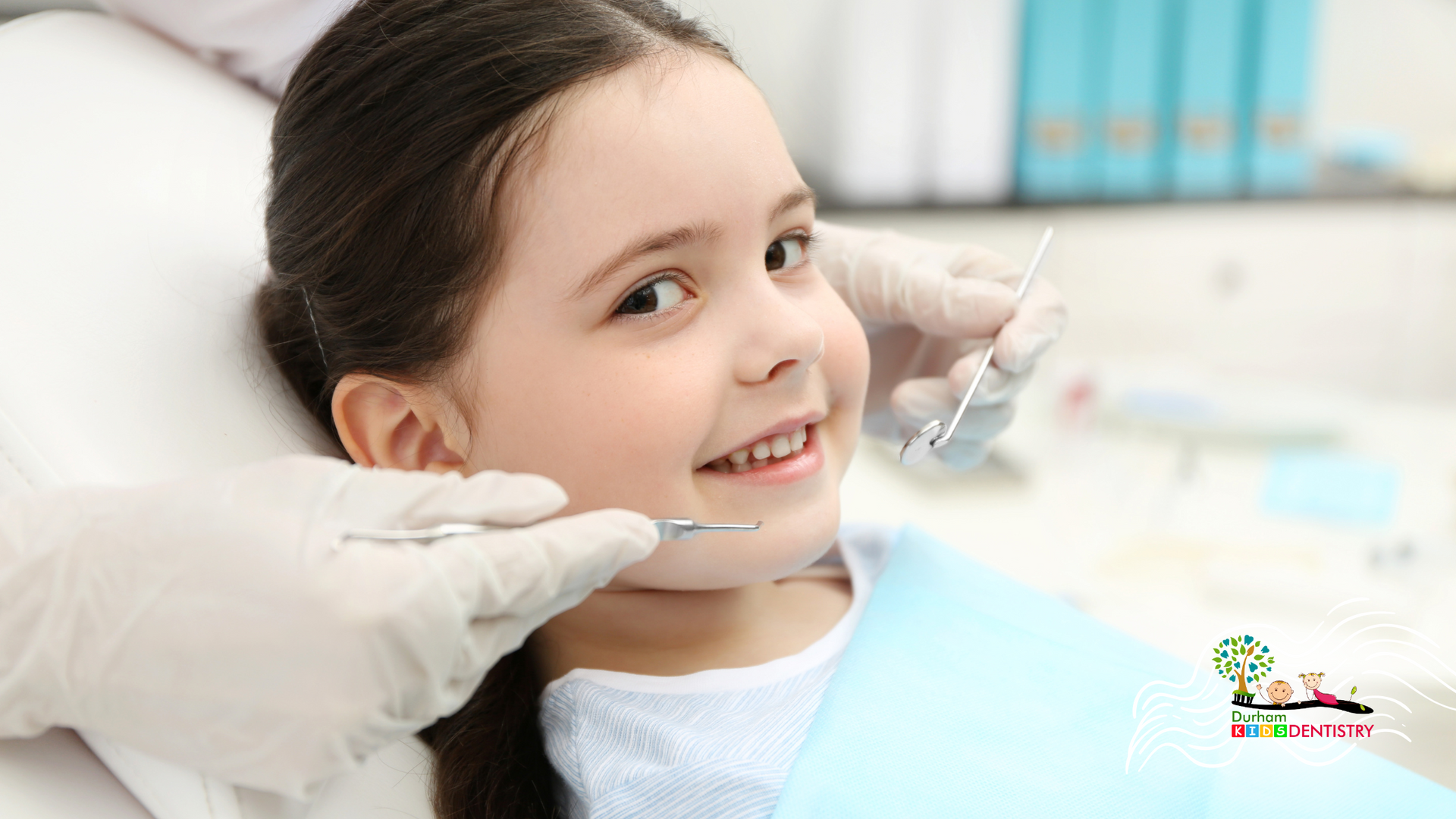 A little girl is sitting in a dental chair getting her teeth examined by a dentist.