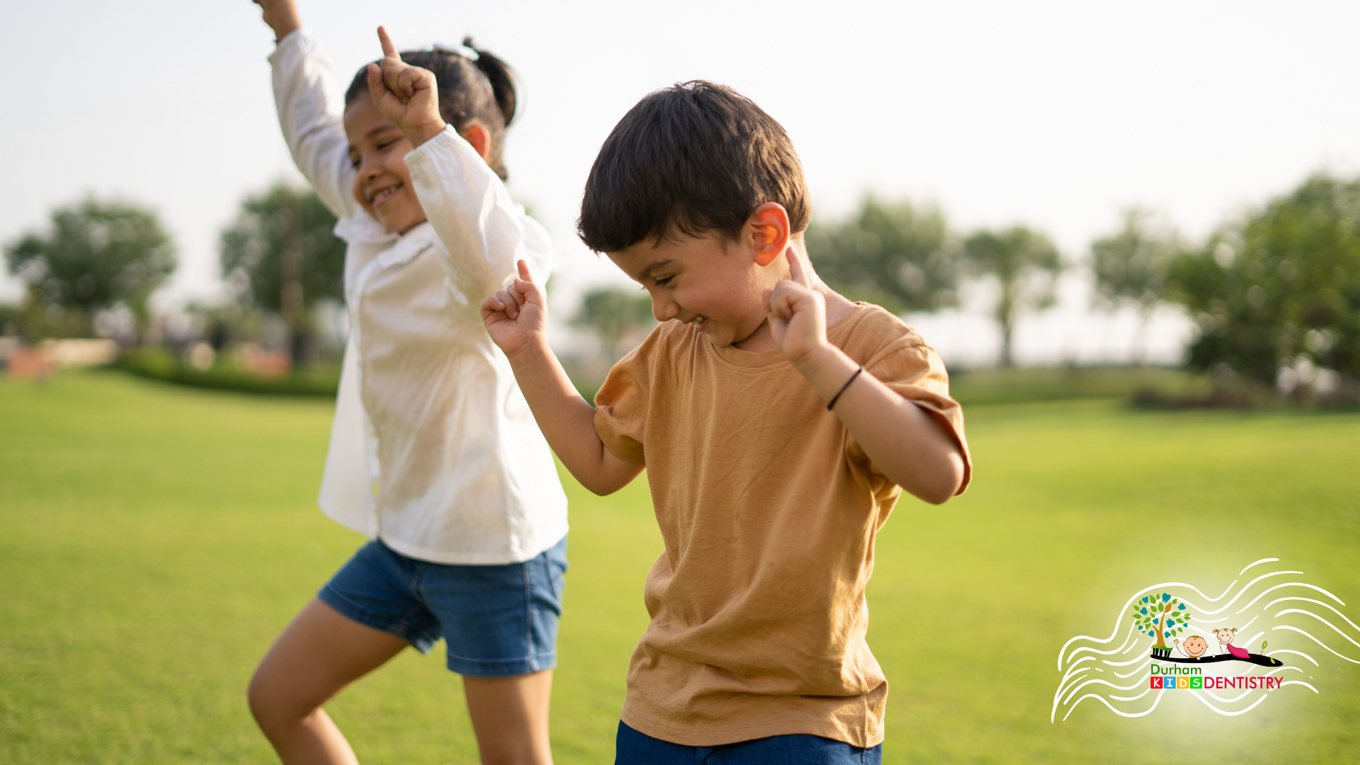 A boy and a girl are dancing in a park.