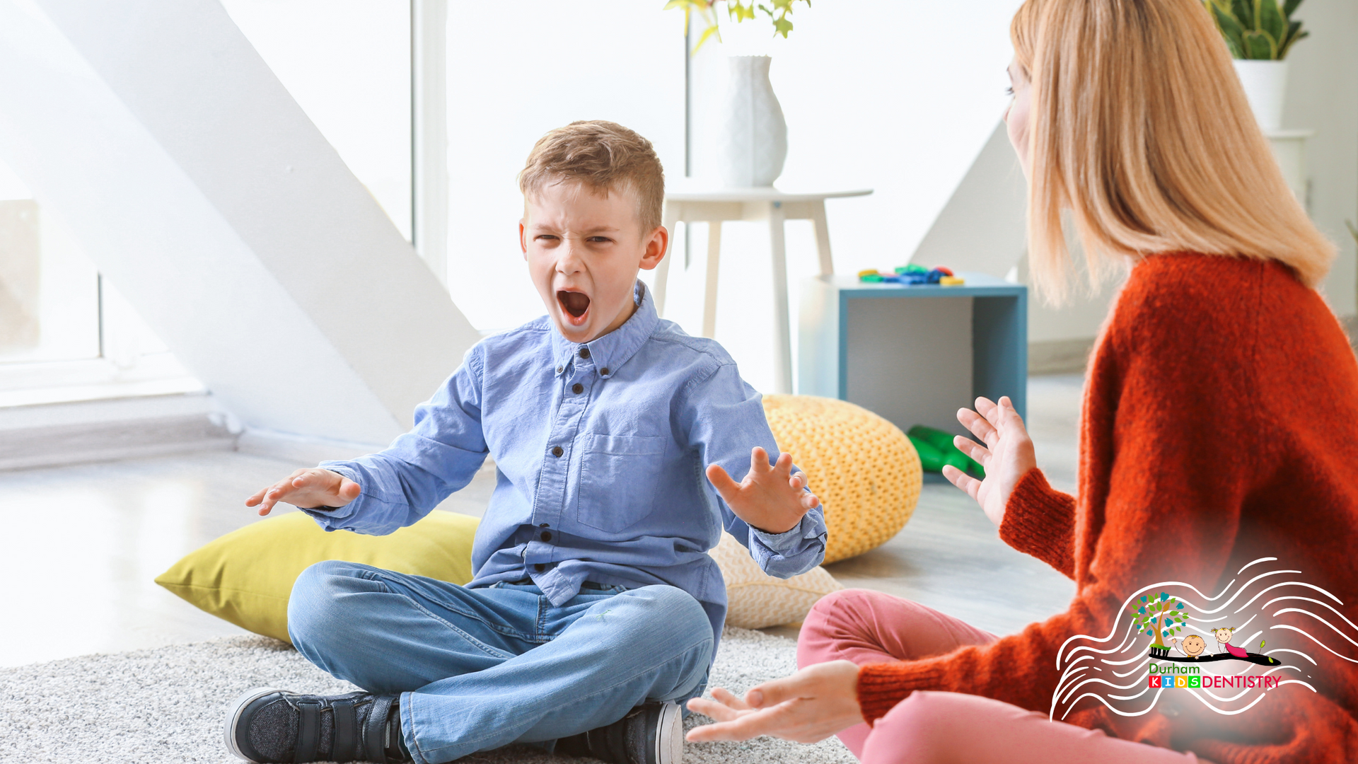A woman and a boy are sitting on the floor talking to each other.