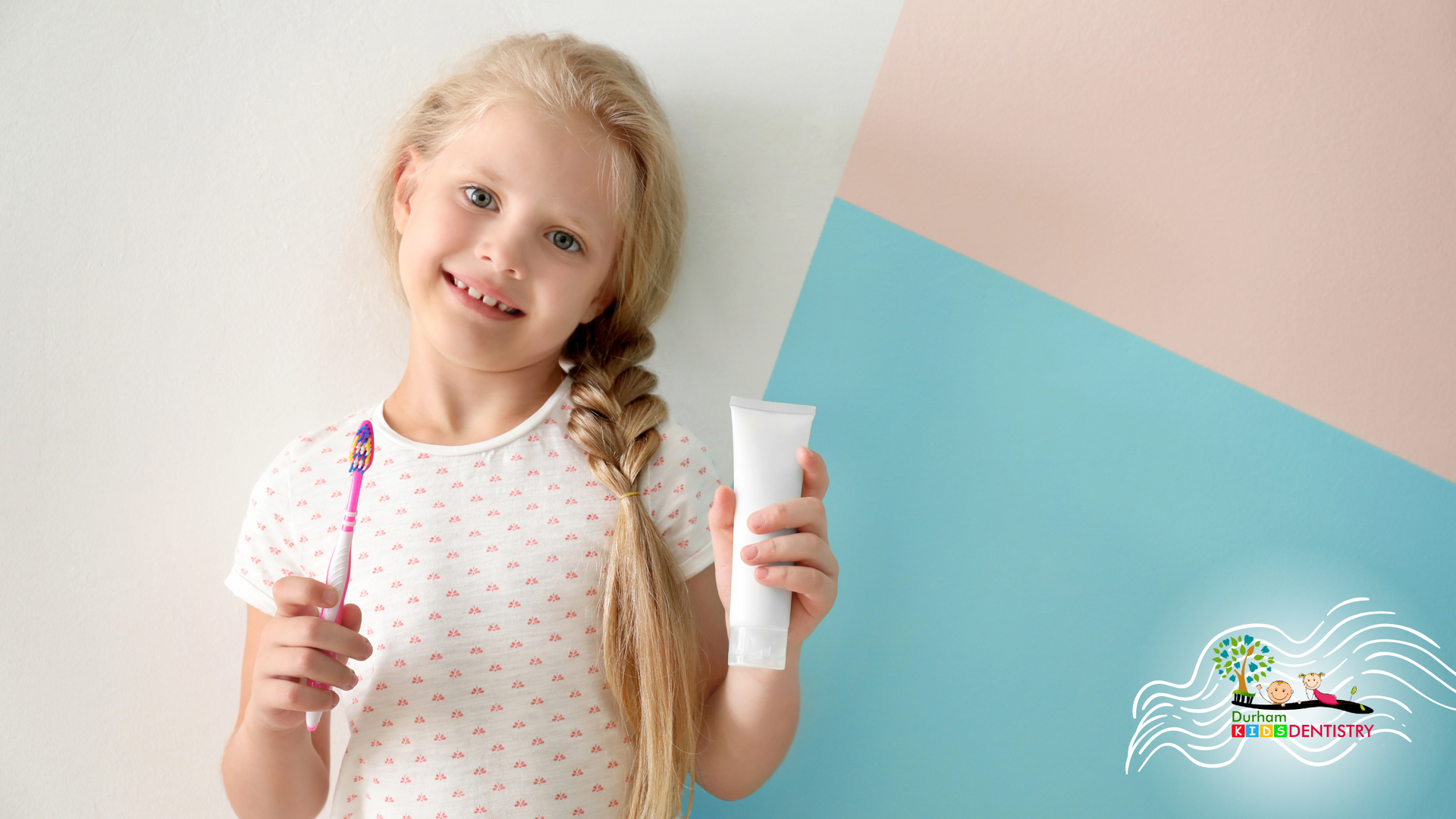 A little girl is brushing her teeth and holding a tube of toothpaste.