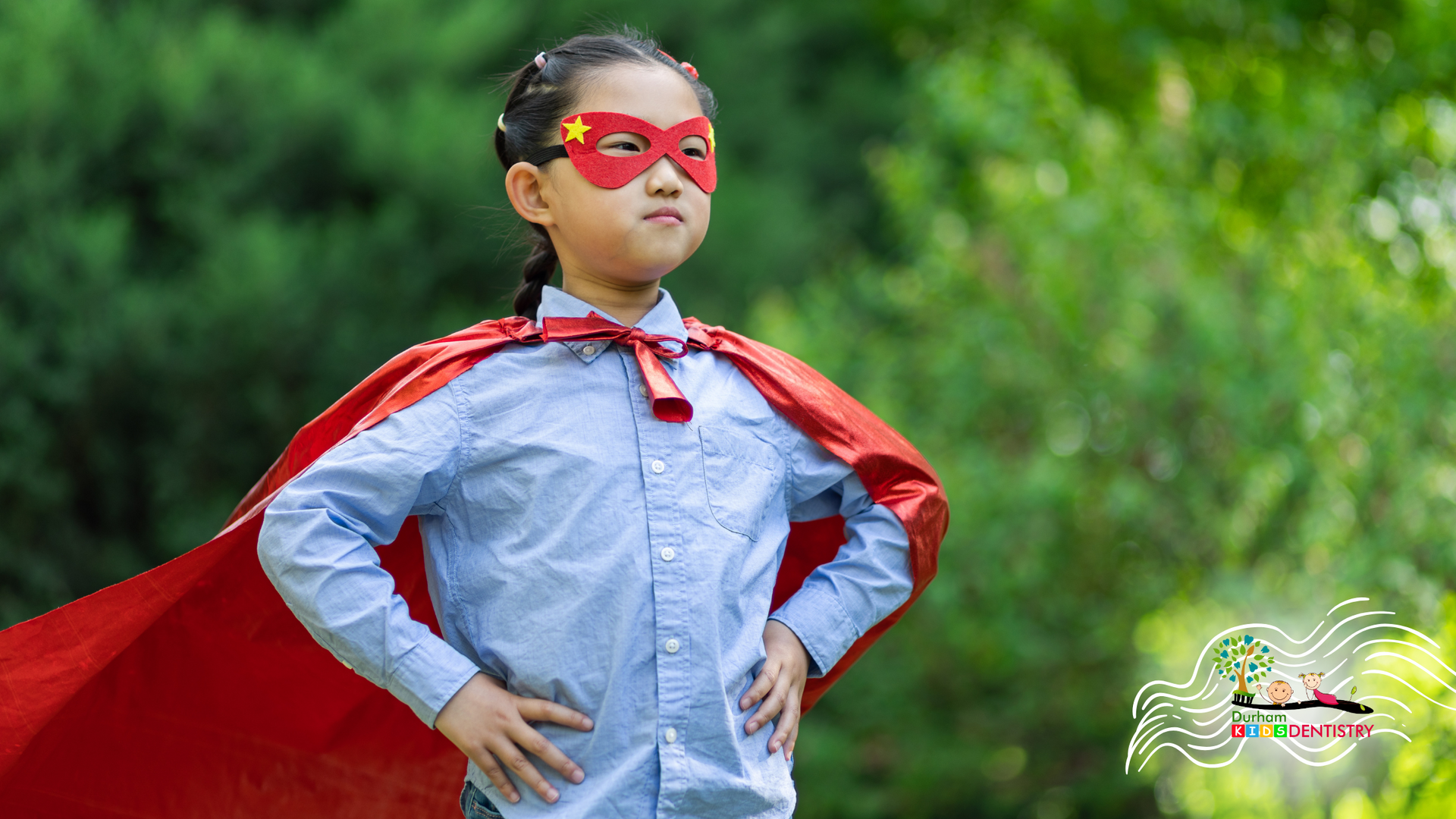 A little girl is wearing a red cape and mask.