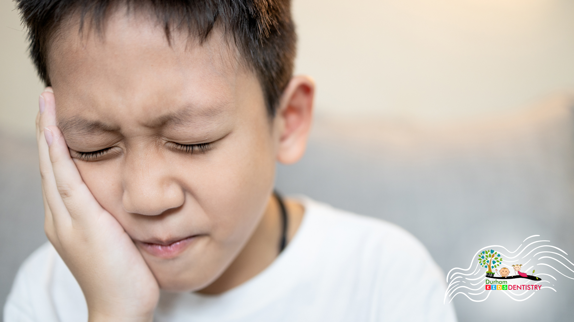 A young boy is holding his face in pain because of a toothache.