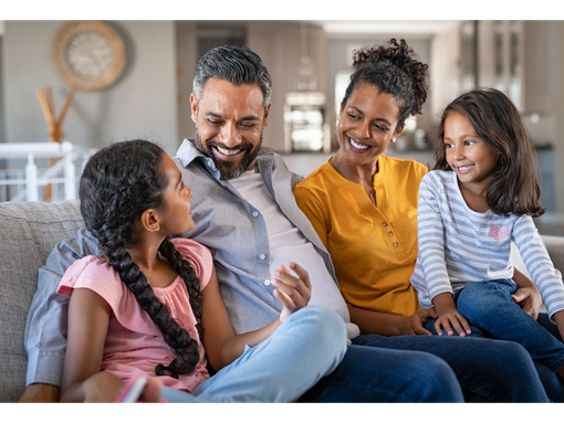 A family is sitting on a couch talking to each other.