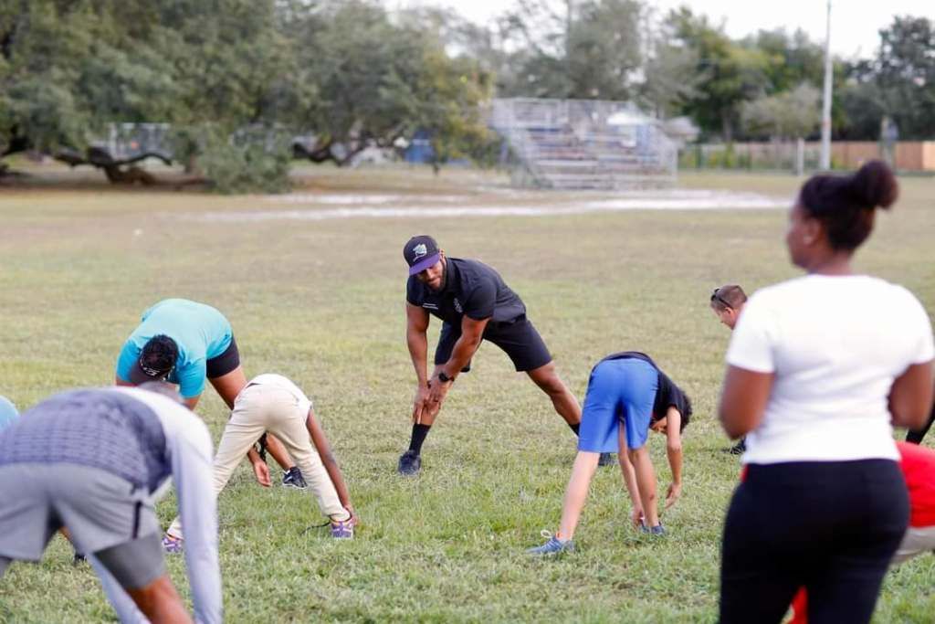 A group of people are doing stretching exercises in a field.