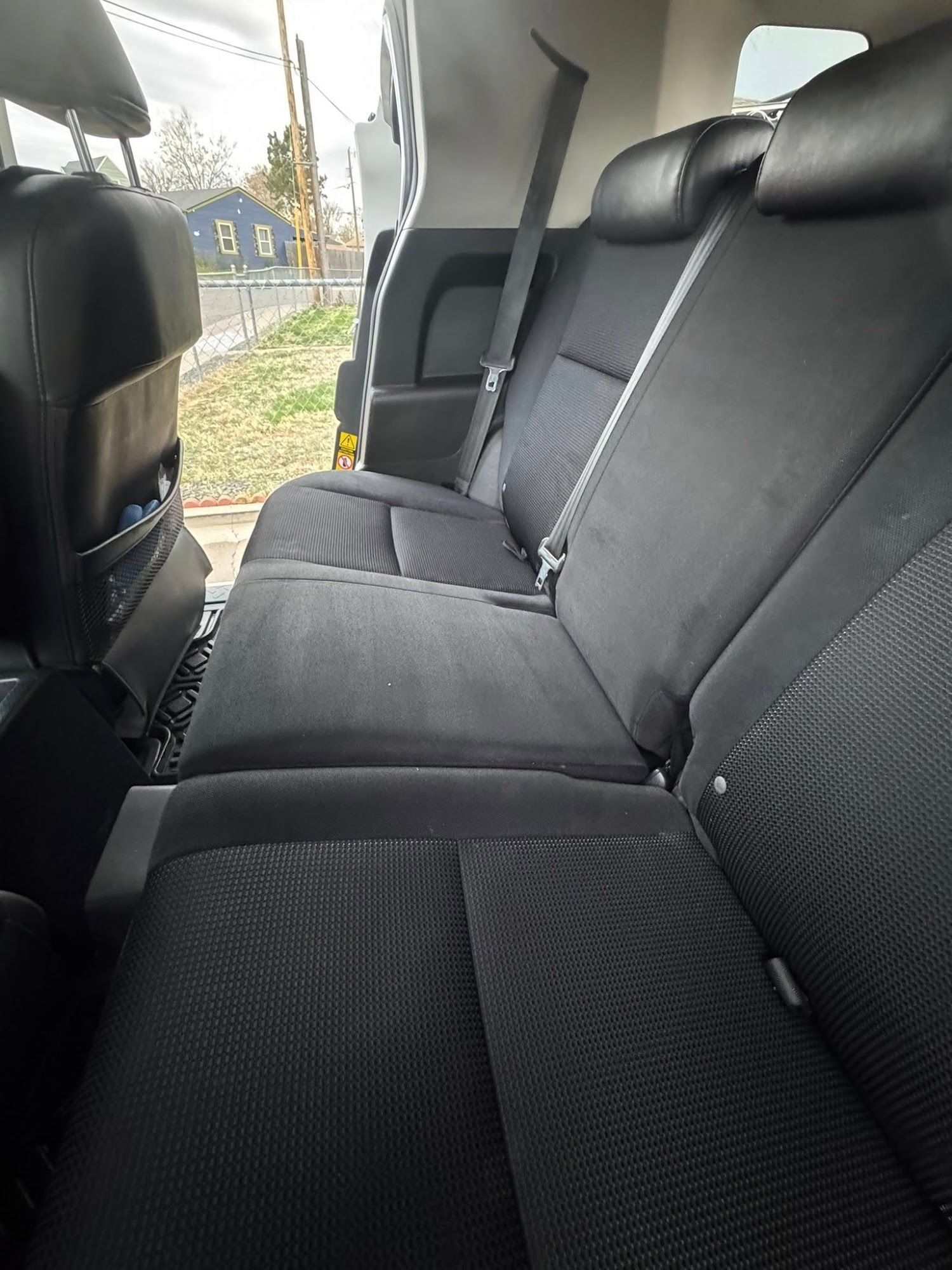 Black car seats in a vehicle interior with seatbelts and headrests, next to a window.