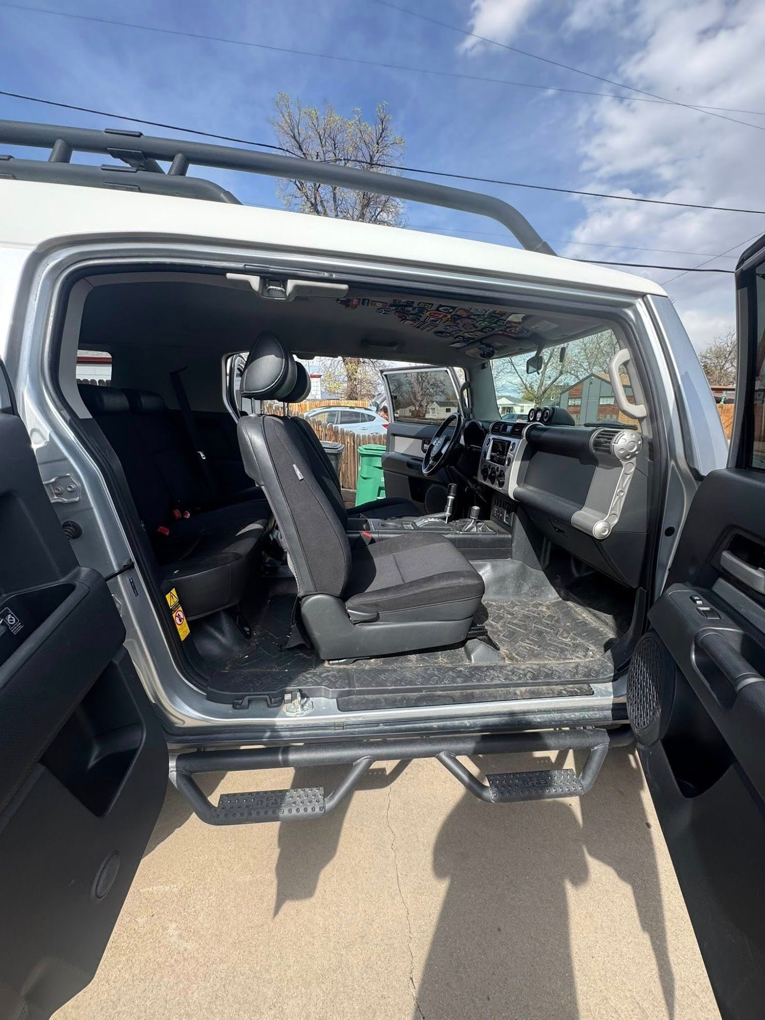 White and black Toyota FJ Cruiser with open doors, showing interior details and side step bars